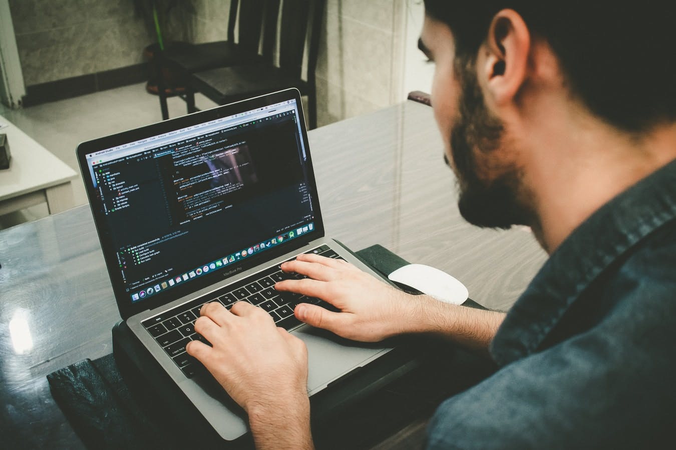 man writing code in a text editor on a macbook pro laptop